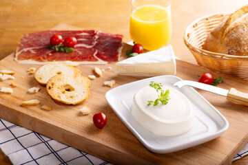 Cream Cheese spread on a black tray with prosciutto, cheese, butter, bread toasts and bread. A...