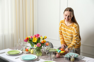 Obraz na płótnie Canvas Woman setting table for festive Easter dinner at home