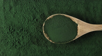 Organic spirulina powder in wooden spoon background and texture, top view