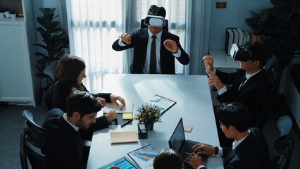 Top view of manager working on laptop and sending data analysis to business people by using VR glass headset while diverse team planning marketing strategy and looking at financial graph. Directorate.