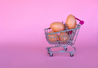 shopping cart full of eggs on a pink background, happy easter greeting card