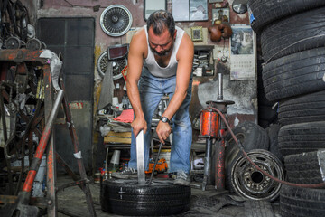 tire repair man remove damaged tire with hand tools from rim to patch it
