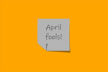Grey sticky note over a yellow background. april fools day
