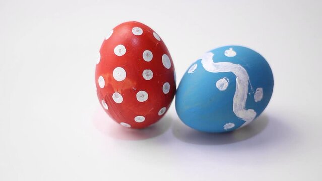 Happy Easter video. Blue egg with dotted and zigzag pattern spins and hits red chicken Easter egg with polka dots on white table. Concept of dance, battle, rotation, twisting, celebration, holiday