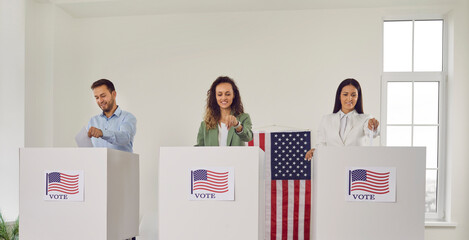 American voters at ballot station during presidential elections. Group of three happy smiling...