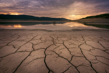 Sunset at the Yesa reservoir, Navarra, during a time of severe drought with the ground cracked by...