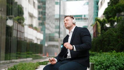 Caucasian businessman listening relaxing music while hold mobile phone. Skilled happy executive...