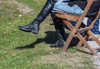 Women's boots slightly out of focus while sitting on a wooden chair.