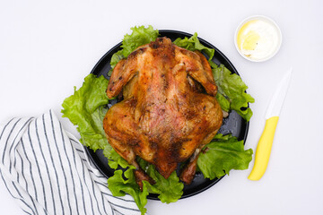 Chicken grill on lettuce on leaves on black plate with sauce cream isolated on white background with napkin.