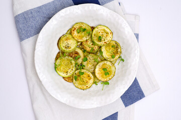 Fried zucchini with lemon zest and thyme with napkin on white background. Top view.