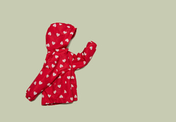 Child's raincoat red color with white heart. Baby girl outwear on blue background