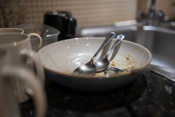 Dirty dishes at night time in the kitchen. Chores to be done at the end of the day. Spoons with...