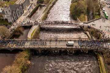 Top down aerial view of Salmon Weir Bridge, Galway. Saint Patrick's day parade on a sunny day
