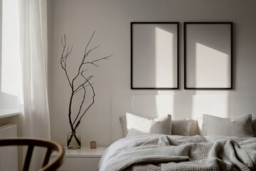 Mockup of two poster frames (DinA) in a bedroom interior. Poster frames hang on a gray wall in the bedroom with minimalist decor and natural light coming in through the window.
