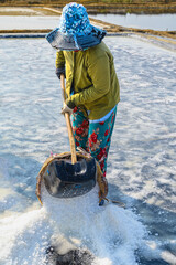 A woman is raking salt into baskets to transport salt to the warehouse in Can Gio district of Ho Chi Minh City, Vietnam