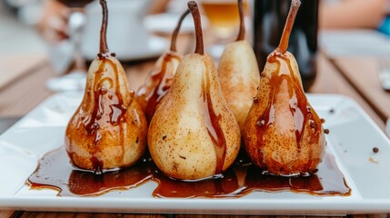 a white plate topped with four pears covered in caramel glaze and drizzled with chocolate.