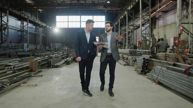 Concept of industrial production in the manufacturing factory in front of the camera walking main manager and engineer and discussing about the future plan of production