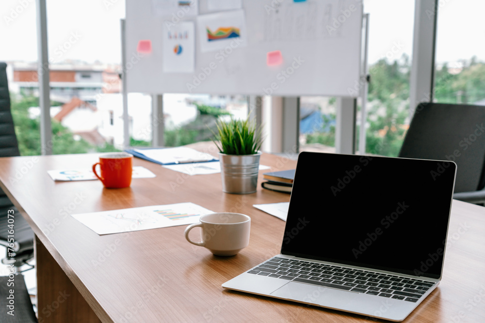 Poster laptop computer with opened lid on table in meeting room of office workspace. uds