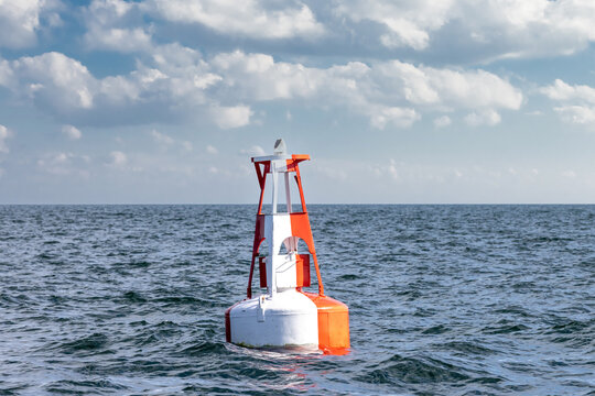 A red and white fairway bouy in choppy water on a cloudy day