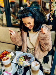 Young pretty brunette woman eating ice cream at the street cafe at Paris, France. Outdoor lifestyle portrait.