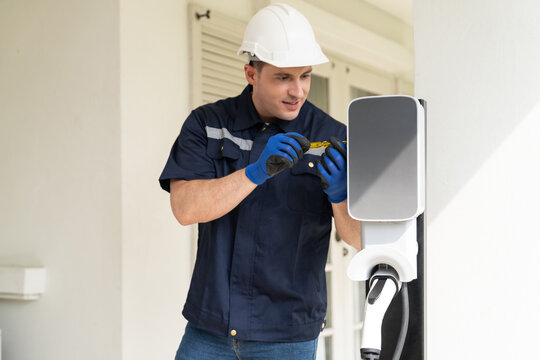 Qualified technician install home EV charging station, providing maintenance service for electric vehicle's battery charging platform at home. EV car technology for residential utilization. Synchronos