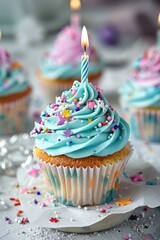 A delicious cupcake with blue frosting and a glowing candle, perfect for birthday celebrations