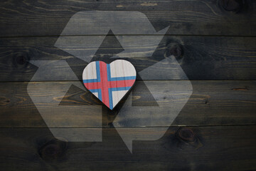 wooden heart with national flag of faroe islands near reduce, reuse and recycle sing on the wooden background. concept