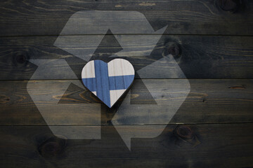 wooden heart with national flag of finland near reduce, reuse and recycle sing on the wooden...