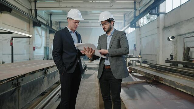 Main engineer and investor have a discussion in the production zone at manufacturing factory they analyse the plan of new project at the end shaking hands