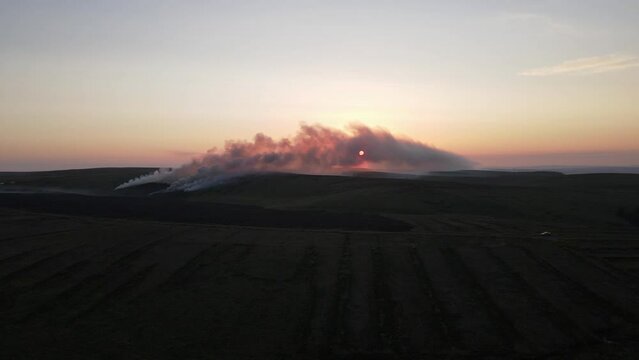 A drone view of the sunset coming through the smoke of a gorse fire at Bragan Mountains, Monaghan, Ireland

