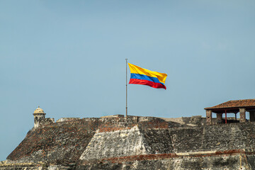 Cartagena, Colombia - July 25, 2023: Gray-beige stone San Felipe de Barajas Fort with national flag...