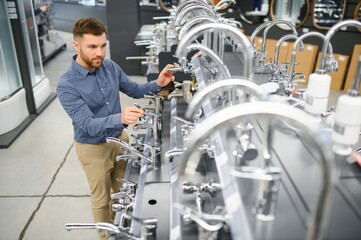 A large selection of water faucets. Man chooses a products in a sanitary ware store