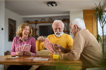 Group of happy seniors having fun while playing cards at home.
