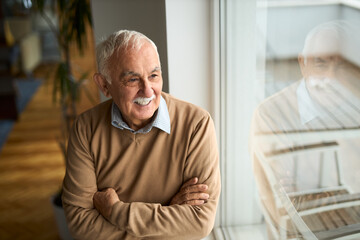 Happy  mature man looking through window at home