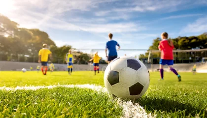 Foto op Plexiglas Fussball im Vordergrund, im Hintergrund Jugendliche die Fussball spielen  © Sina Ettmer