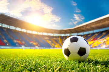 Fototapeta premium Im Vordergrund ein Fussball, im Hintergrund ein leeres Fussballstadion 