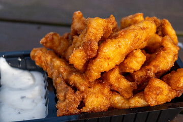 Outdoor eating of diep-fried cod fish pieces served with remoulade sauce, Dutch street food