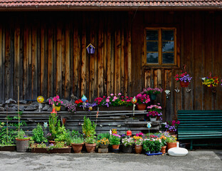 drewniana ławka obok kolorowych kwiatów w doniczkach, kącik wypoczynkowy w ogrodzie, wooden bench next to colorful flowers in pots, relaxation corner in the garden	
