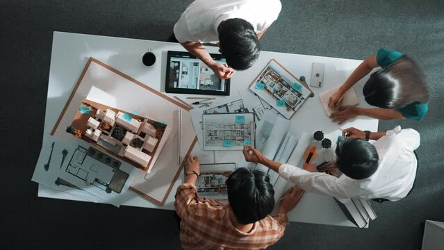 Top down aerial view of architect engineer team writing sticky notes and sticking note at house model while interior designer talking and discussing about building exterior designing. Alimentation.