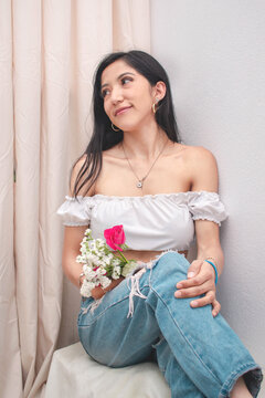 Mujer delgada sonriente sentada con flores en la mano imagen horizontal