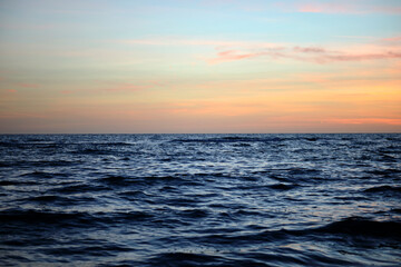 Obraz premium Dramatic red ocean waves at sunset with soft evening sea dark water