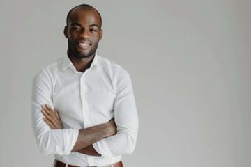 A man with a white shirt and brown pants is smiling and crossing his arms - obrazy, fototapety, plakaty