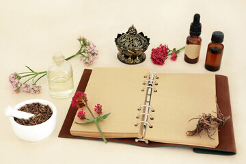 Valerian herb root with flowers, notebook and essential oil bottles. Used in herbal medicine to treat insomnia, is a sedative and tranquilizing natural adaptogen drug.
