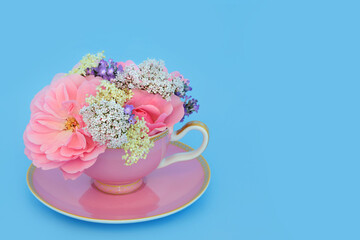 Surreal rose, valerian, lavender and elder flowers in tea cup on blue. Fun food herbal medicine arrangement. Flowers have adaptogen relaxation tranquilizing health benefits. - 765232697