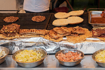 Hamburger meat and chicken grilled on metal crates and sold on a local market - 765234495