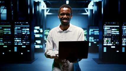 Computer scientist walking between data storage devices in computing server room, ensuring proper...