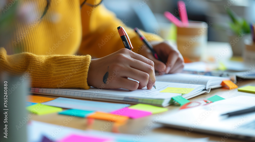Poster a close-up of a non-binary person's hands taking notes during a workshop, their notebook filled with