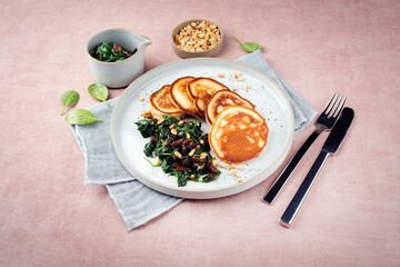 Traditional American pancakes with spinach, pine-nuts and raisins served as close-up on a Nordic...