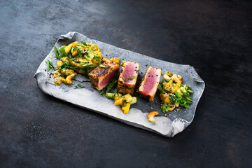 Traditional Japanese gourmet tuna fish steak tataki with tropical fruit tartar and cashew nuts served as close-up on a Nordic design tray with copy space