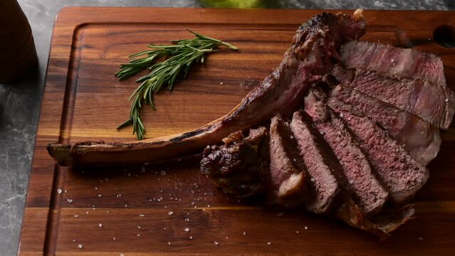 sliced tomahawk steak on wooden board